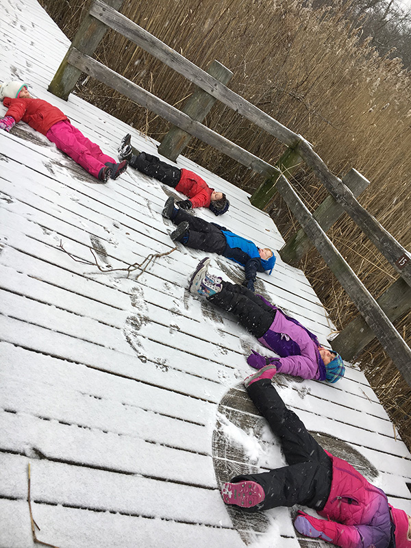 Children making snow angels on the deck