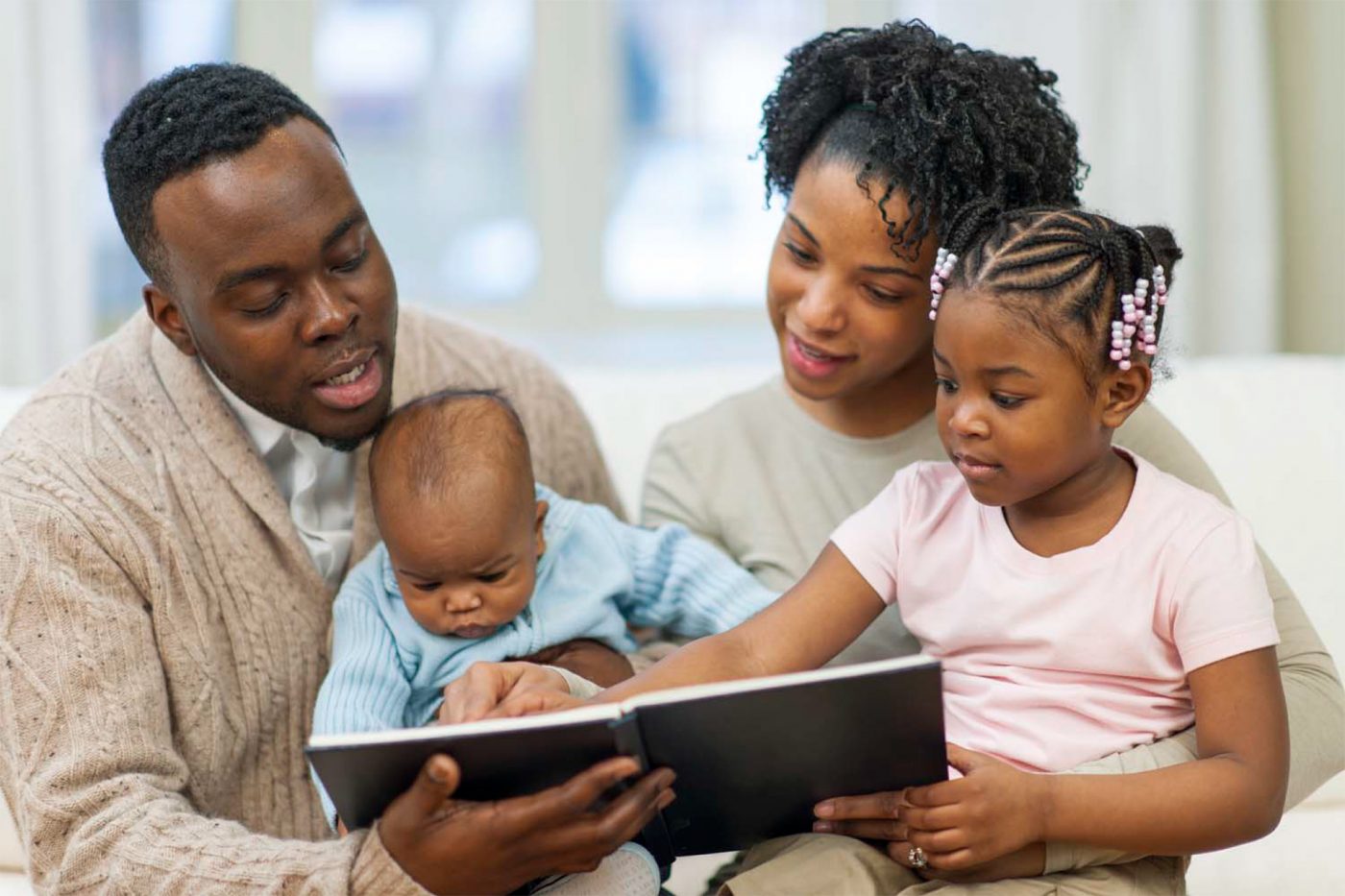 Two African-American parents read to their young children