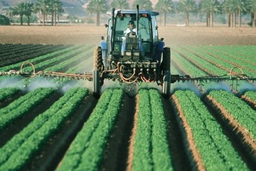 A tractor spraying a large farm field