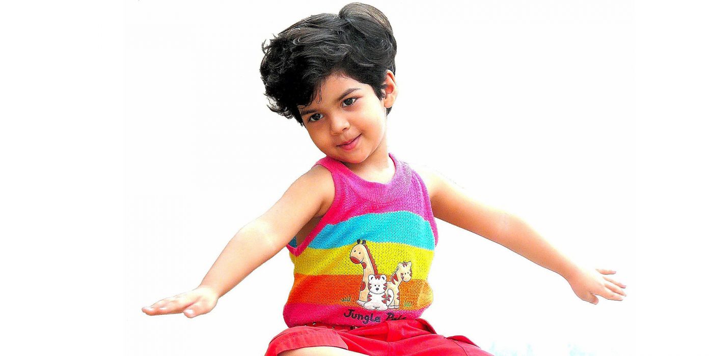 A young child wearing a rainbow tank top stretches